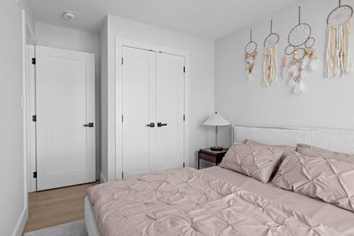 A bedroom with a bed, two doors, and dream catchers on the wall.