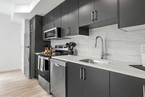 A modern kitchen with dark grey cabinets and stainless steel appliances.