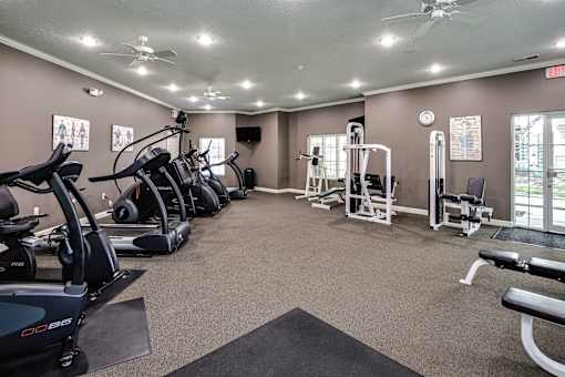 A gym with a variety of equipment including treadmills, weights, and a bench press. at Standing Bear Lake, Omaha