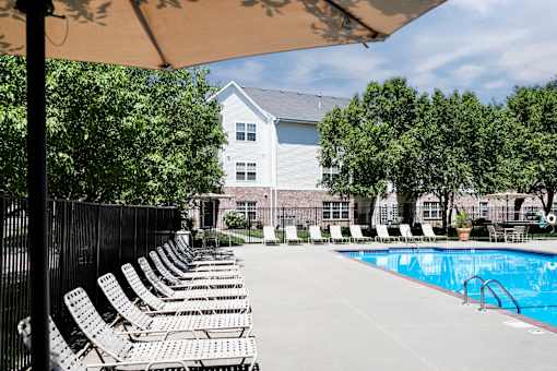 A pool with chairs and a building in the background. at Standing Bear Lake, Omaha