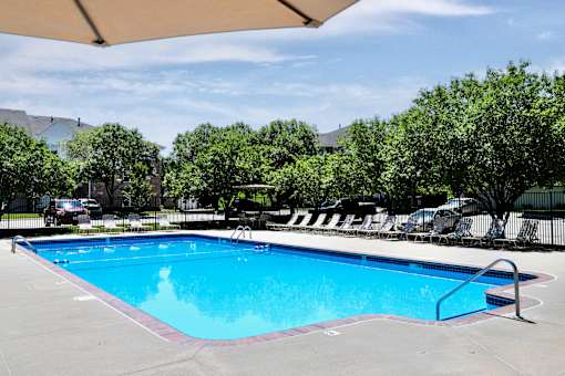 A large outdoor swimming pool surrounded by trees and lounge chairs. at Standing Bear Lake, Nebraska, 68164