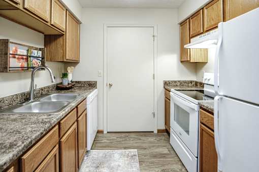 A kitchen with a white refrigerator, sink, and cabinets. at The Pointe, LaVista