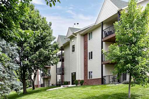 Apartment building with balconies and trees in front. at The Pointe, LaVista, NE