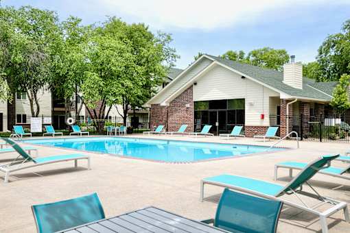A pool with lounge chairs and a building in the background. at The Pointe, LaVista, Nebraska