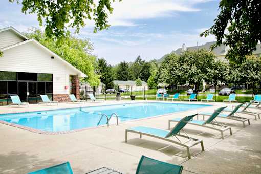 A pool with sun loungers and a building in the background. at The Pointe, LaVista, NE, 68128