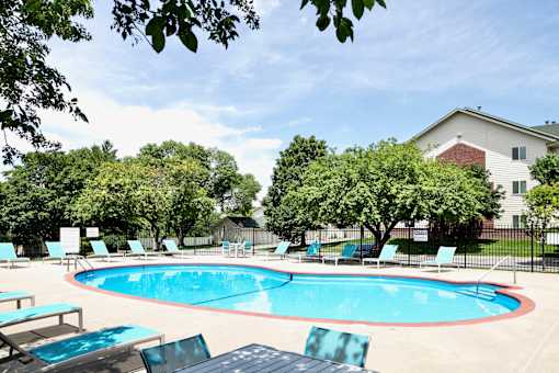 A pool surrounded by trees and chairs. at The Pointe, LaVista, Nebraska