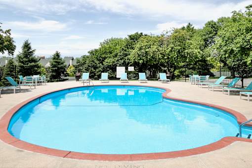 A large outdoor swimming pool surrounded by trees and lounge chairs. at The Pointe, LaVista, NE, 68128