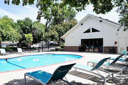 A pool with lounge chairs and a white building in the background. at The Pointe, LaVista, Nebraska