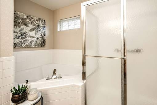 A bathroom with a white tub and a glass shower door. at Tranquility Pointe, Nebraska