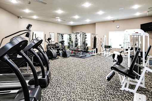A gym with a variety of equipment including treadmills, weights, and a bench press. at Tranquility Pointe, Nebraska, 68164
