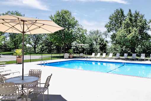 A pool with chairs and an umbrella. at Tranquility Pointe, Nebraska, 68164
