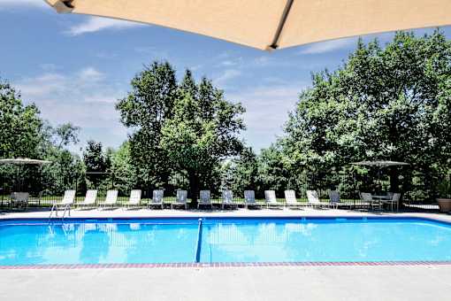 A large swimming pool surrounded by trees and lounge chairs. at Tranquility Pointe, Omaha, NE