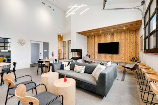 A modern living room with a grey couch, wooden chairs, and a flat screen TV.