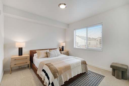 A bedroom with a bed, nightstand, and window.