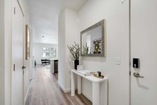 A hallway with a mirror and a table with a vase of flowers on it.