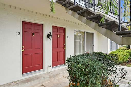 A white house with red doors numbered 12 and 11.