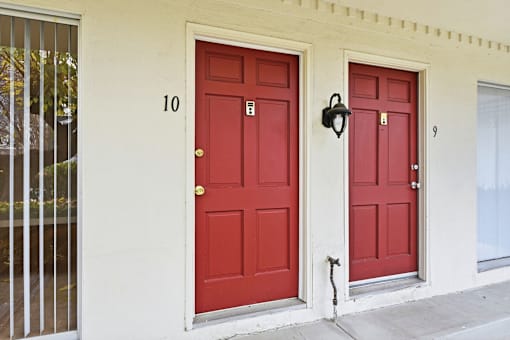 Two red doors on a white building with the numbers 10 and 9 on the wall.