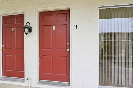 Two red doors with gold knobs and a lamp on the wall.