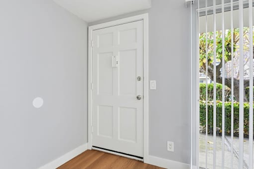 A white door is in a room with a white wall.