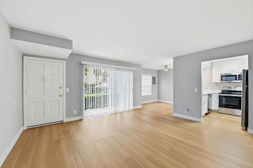 A spacious living room with wooden floors and white walls.