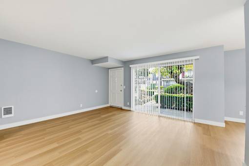 A room with light blue walls and wooden flooring with a sliding glass door.