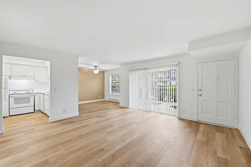 A spacious room with wooden flooring and white walls.