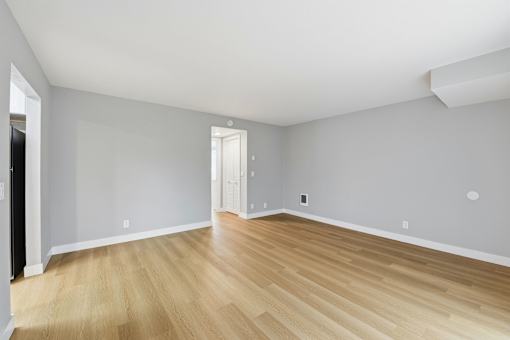 A room with wooden flooring and white walls.