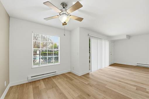 A room with a ceiling fan and a window with blinds.