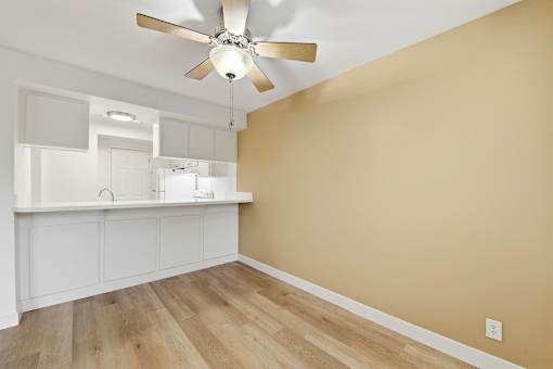 A room with a ceiling fan and wooden flooring.
