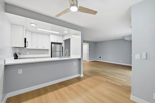A kitchen with a fan and wooden floors.