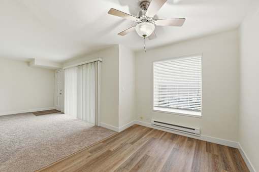A room with a ceiling fan and a window with blinds.
