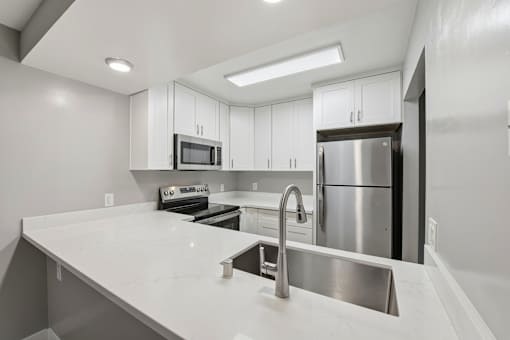 A modern kitchen with a white countertop and stainless steel appliances.