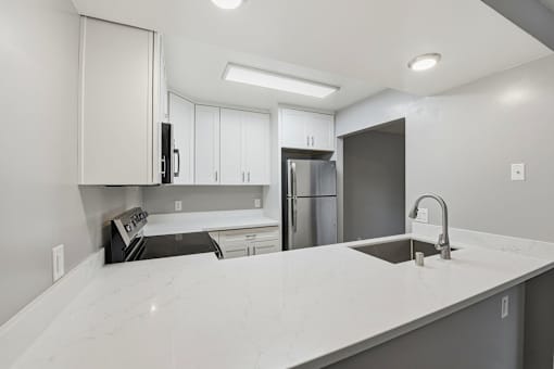 A kitchen with white cabinets and a marble countertop.