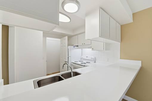 A modern kitchen with white countertops and stainless steel appliances.