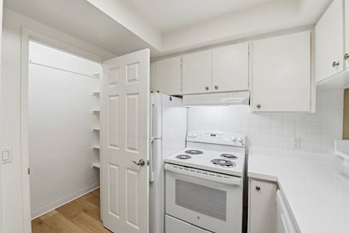 A white kitchen with a stove, oven, and refrigerator.