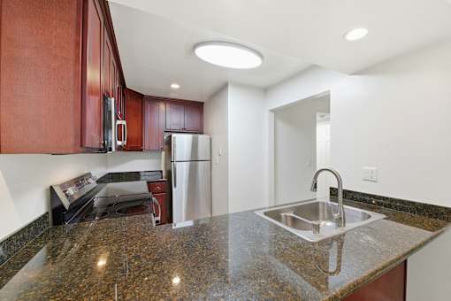 A kitchen with a granite countertop and stainless steel appliances.