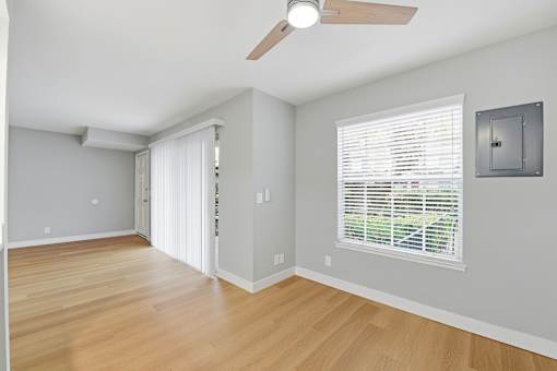 A room with a ceiling fan and a window with blinds.