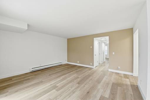 A room with wooden flooring and white walls.