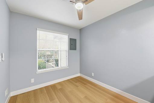 A room with a ceiling fan and a window with blinds.