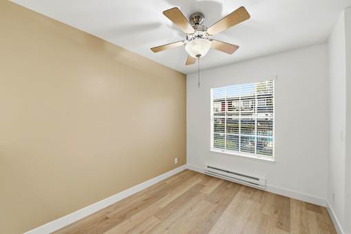 A room with a ceiling fan and a window with blinds.