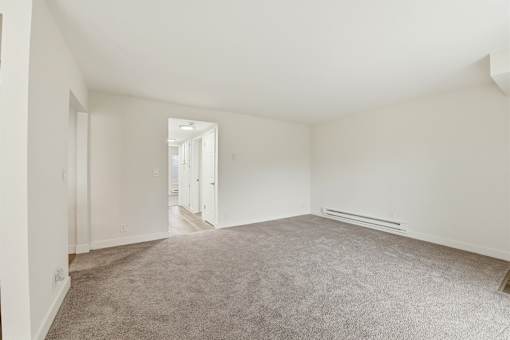 A large empty room with carpeted floor and white walls.