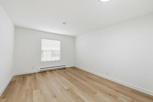 A room with wooden flooring and a window with blinds.