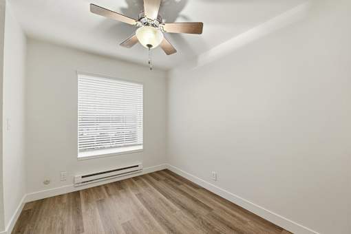 A room with a ceiling fan and a window with blinds.