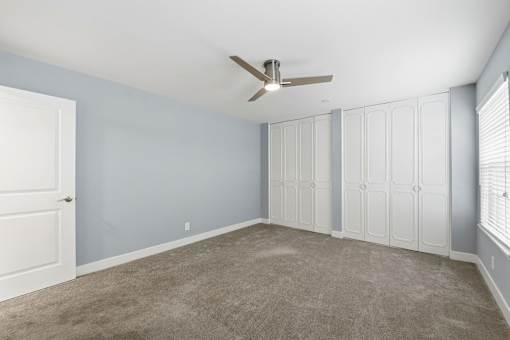 A room with a ceiling fan and a door.