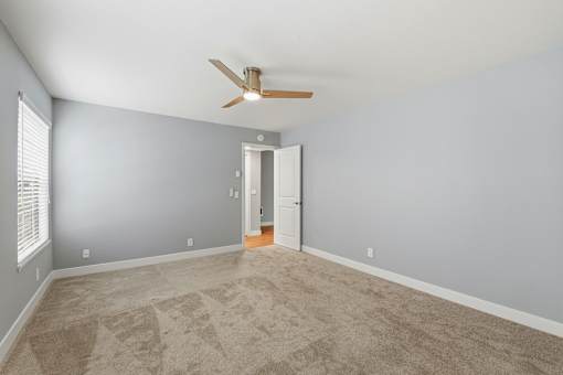 A room with a ceiling fan and carpeted floor.