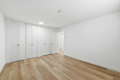Closet with white doors and wooden floor.