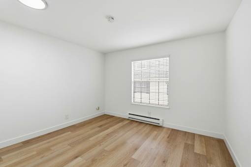 A room with wooden flooring and a window with blinds.