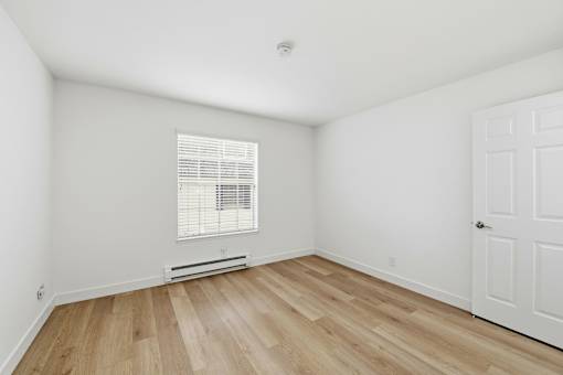 A room with a white door and a window with blinds.