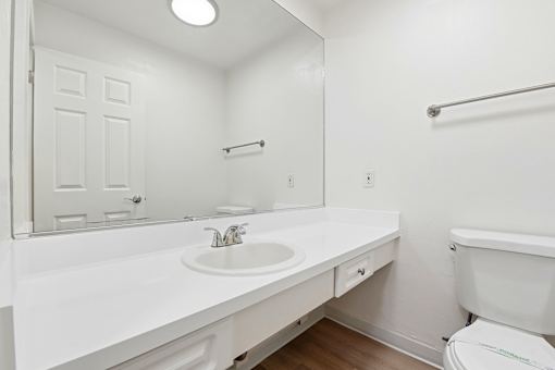A white bathroom with a toilet, sink, and mirror.