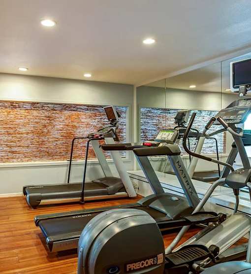 the gym has a large screen tv and a treadmill